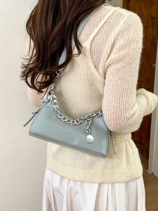 Chic light blue leather shoulder bag with silver chain and metal charm on female model