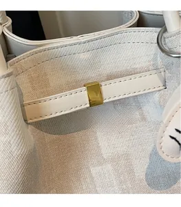 Close-up of cream monogram tote with textured leather and gold hardware detail