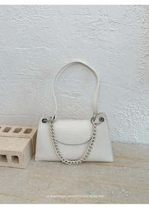Detail of off-white lychee texture leather bag with elegant chain and brand logo