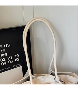 Detail of off-white canvas tote bag featuring slender straps and silver ring connectors