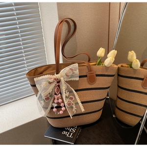 Détail du sac cabas en paille avec rayures noires et nœud en dentelle brodé de fleurs