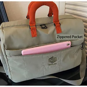 Detail of grey-green nylon travel bag with orange handle and tablet in zipper pocket