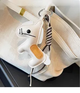 Close-up of a white and orange horse-shaped leather charm on a canvas tote bag