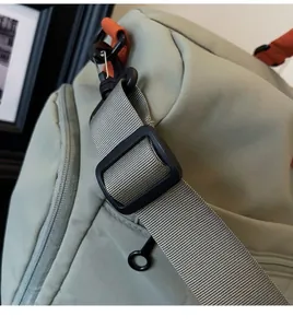Detail of adjustable nylon shoulder strap with metal hook on green travel bag