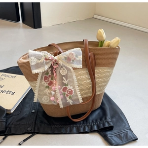 Détail du sac cabas en paille avec nœud en dentelle et broderie rose sur cuir