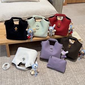 Détail de sacs à main en cuir mat coloré avec fermoirs croisés et breloques en tricot