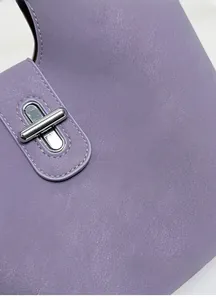 Gros plan d'un sac seau en cuir lavande avec fermoir pivotant en métal argenté