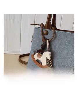 Detail of light blue Saffiano leather bag with brown handle and horse charm