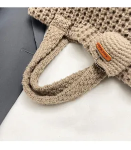 Close-up of beige crochet handbag featuring handmade bear charm and leather tag