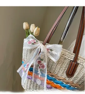 Detail of handmade straw tote bag with lace bow and colorful woven stripes