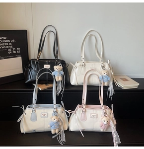 Multiple glossy faux leather tote bags in black, cream, blue, and pink with bear charms