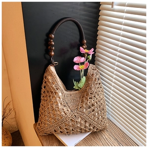 Dettaglio della trama traforata della borsa in paglia con perline in legno sul manico