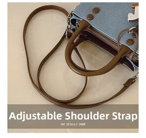 Detail of adjustable leather strap and denim fabric texture on a square crossbody bag