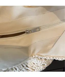 Close-up of smooth metal zipper and woven texture on a beige pastoral shoulder tote bag