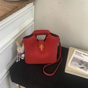Détail du sac seau rouge mat avec boucle dorée et breloque peluche de chiot mignonne