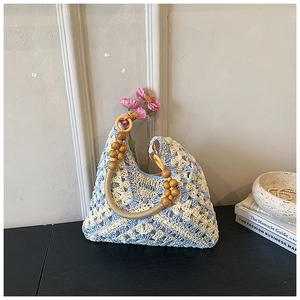 Dettaglio borsa shopper all'uncinetto con motivi geometrici blu e manici in legno