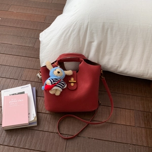 Détail du sac bandoulière en cuir rouge avec boucle dorée et pendentif lapin mignon