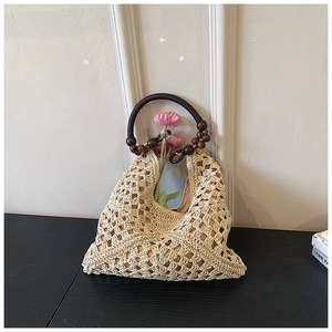 Dettaglio della borsa tote intrecciata con manico tondo in perline di legno e stile boho