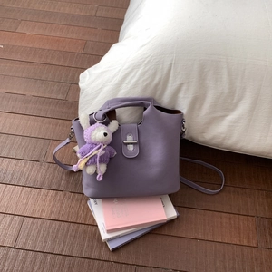 Détail du sac seau violet avec breloque lapin en tricot sur la surface en cuir