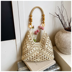 Dettaglio della borsa tote intrecciata con trama naturale e perle di legno decorative