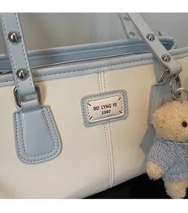 Close-up of dual-tone shoulder bag with vintage patch and cute bear plush charm