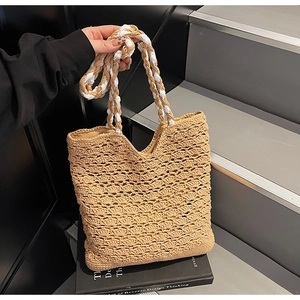 Detail of woven hollow pattern and dual-tone rope handles on khaki straw tote bag