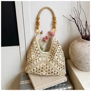 Dettaglio della borsa tote in maglia traforata con accenti di perline di legno e fiori