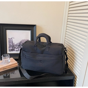Close-up of a black travel bag featuring a reinforced handle and front zipper pocket