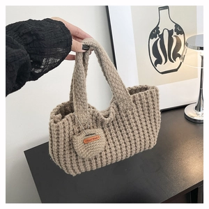 Detalle de bolso de punto grueso hecho a mano con textura de gofre y un mini bolso a juego