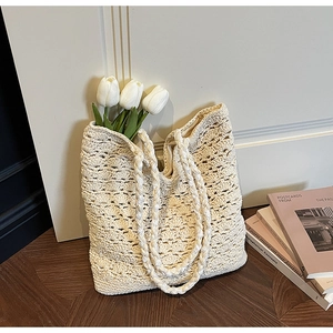 Detail of hollow woven tote bag in cream cotton with decorative tulips in warm lighting