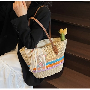 Detail der handgewebten Strohtasche mit bunten Streifen und Spitzen-Blumenschleife