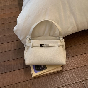 Dettaglio borsa in pelle martellata bianco crema con fibbia argento su una pila di libri