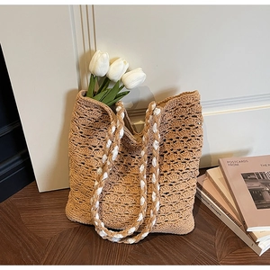 Detail of hand-woven beige tote bag with intricate hollow texture and cord straps