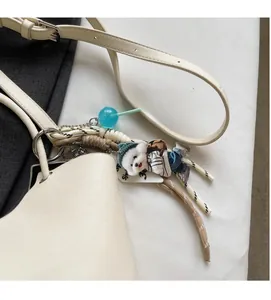 Detail of off-white leather bucket bag featuring unique puppy doll and woven pendants