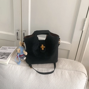 Détail d'un sac seau vintage noir avec fermoir doré et breloque lapin sur un canapé