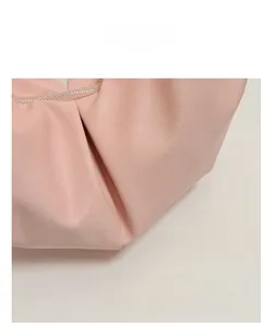 Detail of light pink leather bag showing ruched texture and silver metal zipper closure