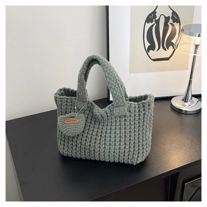 Primer plano del bolso tote de punto verde salvia hecho a mano con adorno de corazón