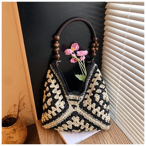 Dettaglio borsa tote intrecciata con motivi geometrici e manici rotondi in perle di legno