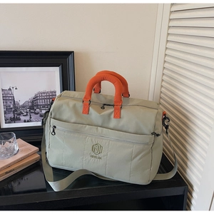 Detail of large nylon travel bag with orange handles and adjustable shoulder strap