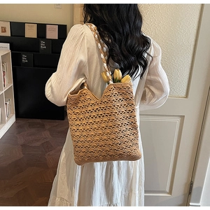 Detail of woven straw tote bag with wavy cutout patterns and braided shoulder straps