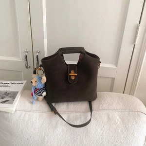 Détail du sac seau rétro marron avec fermoir doré rotatif et breloque ourson en peluche