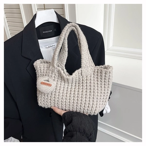 Detalle de bolso de punto beige hecho a mano con textura gruesa y colgante de corazón