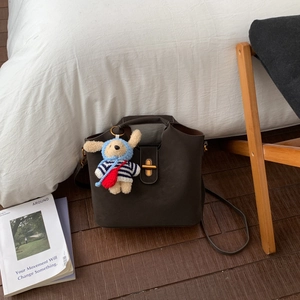 Détail du sac seau rétro avec fermoir doré et pendentif en peluche en forme de chien