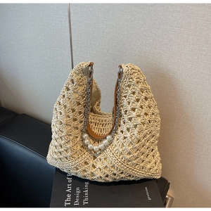 Détail d'un sac cabas en paille tissé main avec chaîne perle et bandoulière cuir