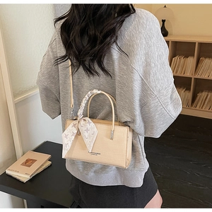 Chic beige crocodile texture handbag with silk scarf detail shown in lifestyle setting