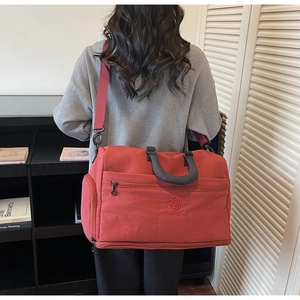 Rear view of large brick red travel bag showing adjustable shoulder strap and scale