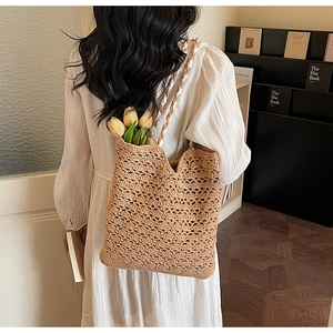 Detailed view of hollow crochet pattern on tan straw tote bag with braided handles