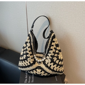 Détail d'un sac cabas en paille tissée avec motifs géométriques et chaîne de perles de luxe