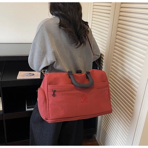 Model carrying a deep red travel bag against a modern library and blinds background