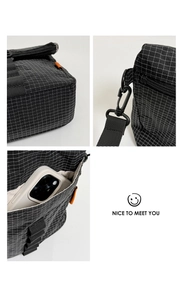 Détail du sac bandoulière à carreaux noirs avec tirettes oranges et poche intérieure pour mobile
